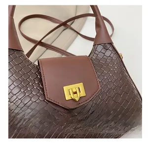 Détail d'un sac en cuir tressé marron foncé avec un fermoir rectangulaire en métal doré
