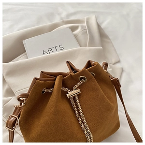 Detail of brown matte suede bucket bag featuring golden chain drawstring and fine texture