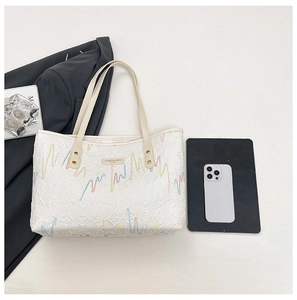 Detail of white tote bag with quilted texture and colorful wavy embroidery on the surface