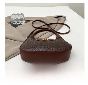 Vue détaillée de la texture cuir tressé marron foncé avec fermoir rotatif carré doré