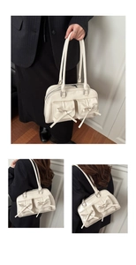 Detail showing the ribbon bow design and dual front pockets on the cream tote bag