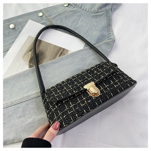 Dettaglio della borsa in tweed nero e oro con chiusura a scatto in metallo dorato lucido