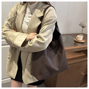 Detailed close-up of dark brown leather woven texture on a large tote handbag
