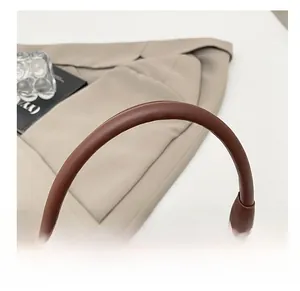 Détail du sac tressé marron foncé montrant la poignée en cuir lisse et les pièces en métal