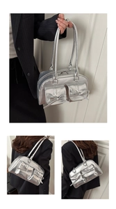 Detail of silver metallic tote bag featuring bow accents and functional front dual pockets