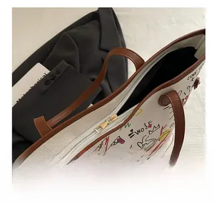 Detail view of smooth golden zipper and brown leather straps on graffiti tote bag