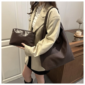 Detail of dark brown woven leather tote bag with matching zippered clutch set