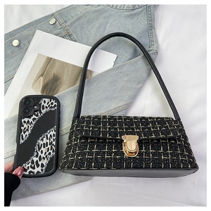 Dettaglio della borsa in tweed nero con trama dorata e fibbia di chiusura in metallo