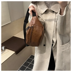Detail of brown PU leather crossbody bag with adjustable black strap and dual zippers