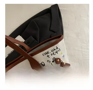 Detail of white graffiti tote bag with brown leather handles and colorful patterns