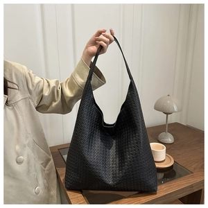 Détail d'un sac hobo tressé noir montrant la texture du cuir et sa grande capacité