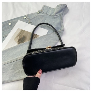 Dettaglio della borsa in tweed nero e pelle con chiusura metallica dorata lucida