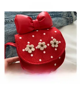 Détail d'un sac bandoulière rouge à pois blancs et petites fleurs en peluche