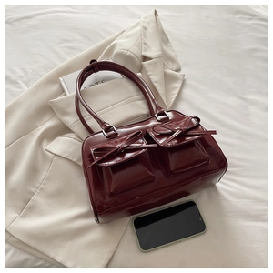 Detail of burgundy bow pillow bag on beige suit with lifestyle props for daily styling