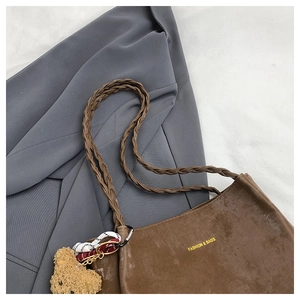 Detail of brown tote bag featuring unique woven rope handles and cute bear pendant
