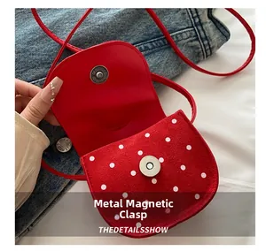 Détail du mini sac rouge à pois avec mécanisme de fermeture magnétique dorée sécurisée