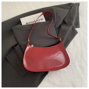 Dettaglio borsa rossa in vernice con cerniera dorata su giacca grigia elegante