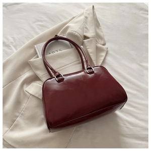 Macro detail of wine red glossy leather tote with elegant silver metal buckles