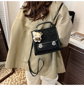 Détail d'un sac en cuir à motif léopard avec deux fermoirs argentés et un charm en peluche