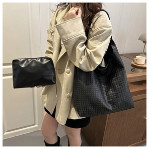 Detail of black woven tote bag and leather pouch shown with a beige trench coat