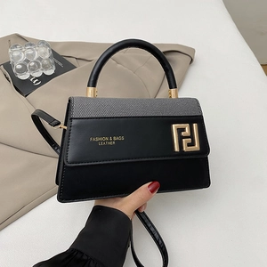 Sac à main minimaliste en cuir noir et tissu avec poignée ronde et fermoir doré chic