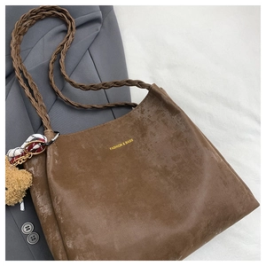 Detail of retro brown tote bag with woven strap, plush bear charm and silk scarf decoration