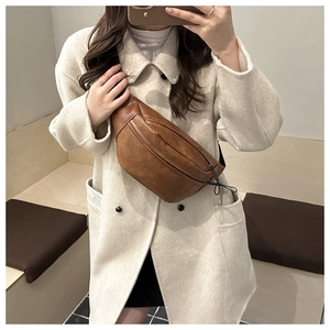 Close-up of a vintage brown leather crescent chest bag shown worn by a model in a mirror