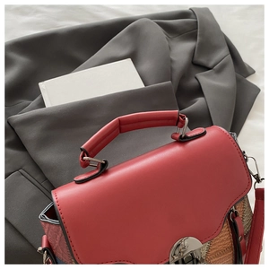 Detail of red leather bag with snakeskin texture patchwork and vintage metal buckle