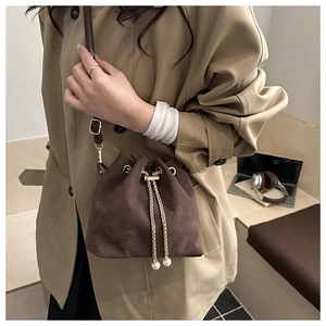 Detail of vintage matte brown bucket bag with gold drawstring and pearl accents