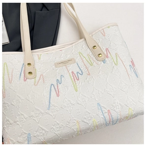 Detail of quilted tote bag featuring multi-color wavy embroidery and leather logo patch