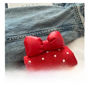 Détail d'un mini sac rouge à pois avec fleurs en feutre et un grand nœud en similicuir