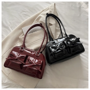 Detail view of retro high-gloss leather shoulder bags with bow pockets in burgundy and black