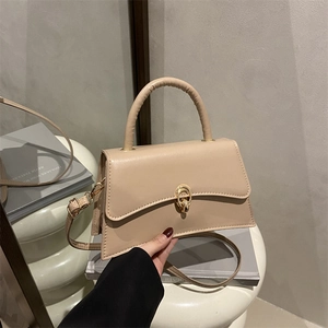 Beige strukturierte Umhängetasche mit gewellter Klappe und goldenem Verschluss auf Podest