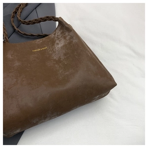 Close-up of vintage brown tote bag with gold lettering and woven texture strap