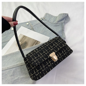 Dettaglio borsa a spalla in tweed nero e oro con chiusura in metallo e tracolla in pelle