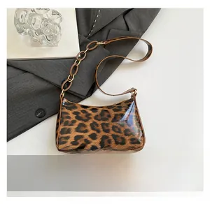Detail view of leopard print crescent bag with acrylic chain showing compact size scale
