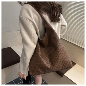 Brown woven tote bag side view on shoulder showing large capacity and texture
