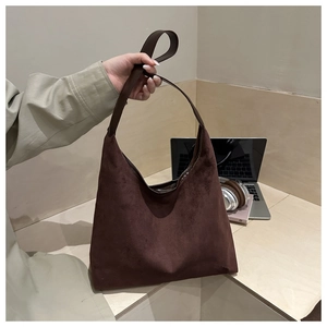 Close-up of deep brown suede tote bag with wide strap in an office lifestyle setting