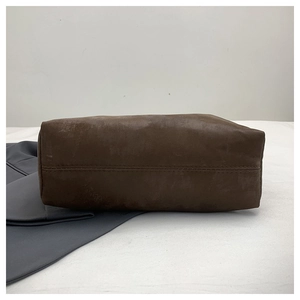 Detailed macro view of the stitched seam on a dark brown matte leather tote bag bottom