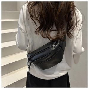 Rear view of a black leather crescent chest bag worn over a white oversized hoodie