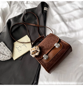 Détail du sac léopard avec boucles argentées et pendentif de poupée en peluche doux
