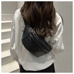 Detail of black faux leather chest bag with double zippers and long pulls on the back