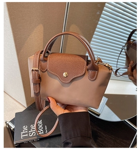 Detail of khaki nylon bag with brown leather trim and contrast stitching on a flap