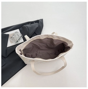 Top-down view of spacious interior with brown lining and zipper closure of cream tote bag