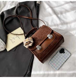 Détail du sac bandoulière vintage marron avec rabat léopard et breloque en peluche