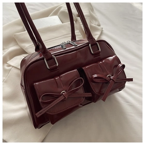Close-up of deep red vintage faux leather shoulder bag with chic bow details and pockets