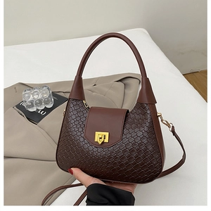 Détail du sac à main marron foncé à texture tressée, anses en cuir et finitions dorées