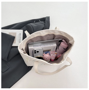 Detail view of a large white tote bag showing storage for tablets, books and umbrellas