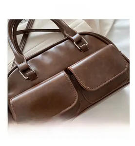 Close-up of brown faux leather bowling bag with silver hardware and dual flap pockets