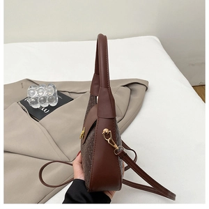 Détail de la texture tressée marron foncé et du fermoir doré sur le sac à main